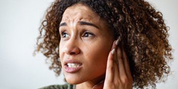 Woman wincing from ear pain