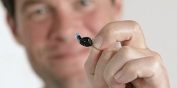 Man holding up the tiny Oticon Zeal™ hearing aid