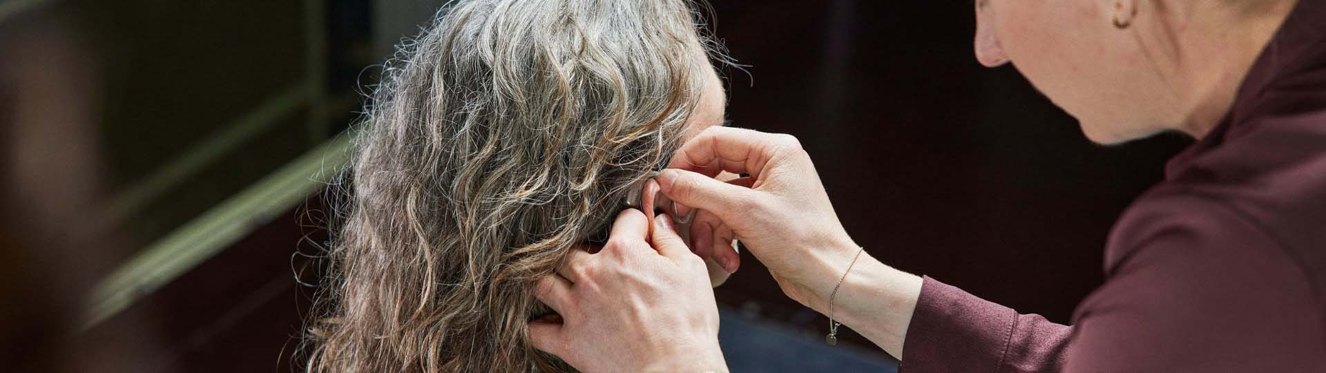 person assisting with hearing aid placement