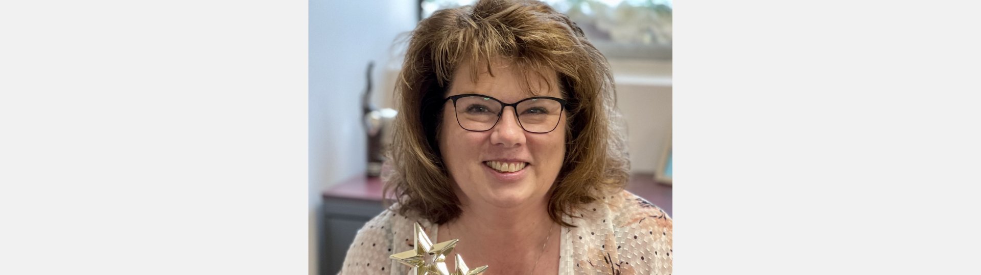 Cathy McCrea holding an award, representing compassionate hearing care services.