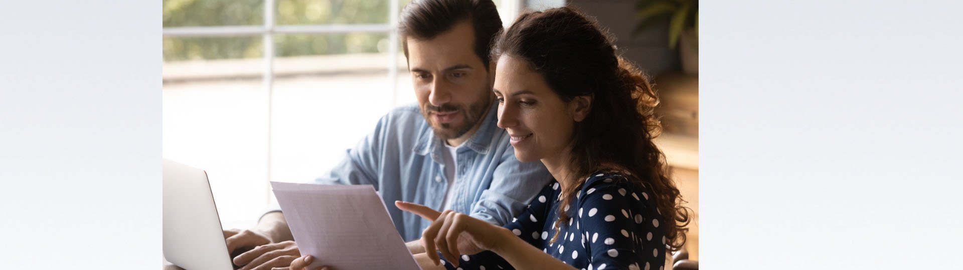 couple reviewing a document while using a laptop