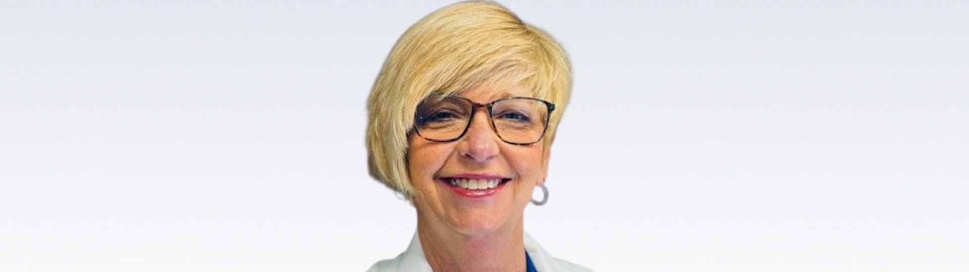 hearing care professional Taunya Hough smiling in a white coat on a light background