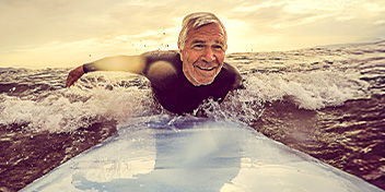 senior surfing enthusiast enjoying the ocean waves at sunrise