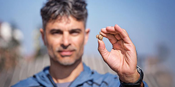 man showcasing a small, modern hearing aid