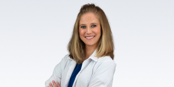 Audiologist wearing a white coat and smiling with arms crossed