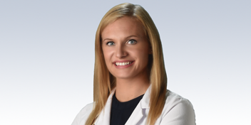 Hearing care professional wearing a white lab coat, smiling confidently