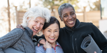 Older adults smiling and holding yoga mats outdoors, promoting active and healthy lifestyles.