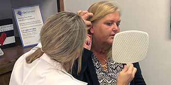 Hearing specialist adjusts hearing aids for a client during a fitting session.