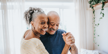 older couple joyfully dancing together in a bright, sunlit room