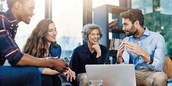 collaborative team discussing ideas around a laptop in a bright and modern office space