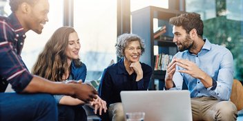 people having a discussion around a laptop in a modern office setting