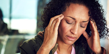 woman pressing her temples, possibly experiencing tinnitus or discomfort