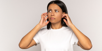 woman demonstrating signs of tinnitus discomfort with hands near her ears