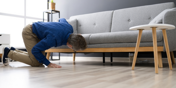 searching for a lost item under a couch in a modern living room
