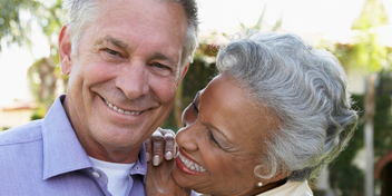 Older couple smiling warmly while enjoying time together outdoors.