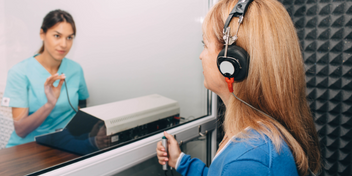 woman receiving a hearing assessment wearing headphones in a soundproof booth