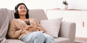 woman enjoying sound therapy with headphones while reclining on a cozy couch