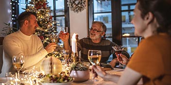 Festive holiday gathering with friends and family enjoying conversation at a decorated table, emphasizing the value of clear hearing in connecting and communicating during celebrations.