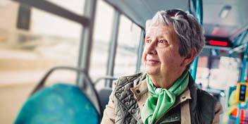 Older adult with hearing loss sitting quietly on a bus, illustrating feelings of loneliness and social isolation.