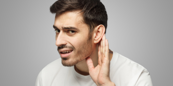 Sudden hearing loss, individual holding hand to ear with a concerned expression