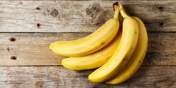 ripe yellow bananas resting on a rustic wooden surface