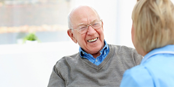 Senior man smiling during a consultation with a hearing care professional.