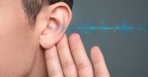 person holding hand up to ear and soundwaves