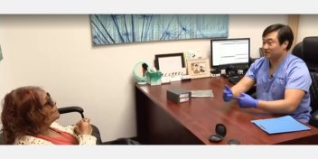 Dr. Daniel Agrusa discussing hearing care options with a patient in an office setting.