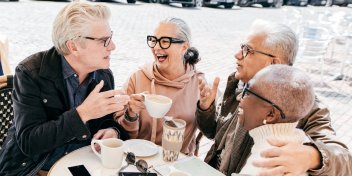 group of older adults enjoying a lively conversation over coffee at an outdoor café