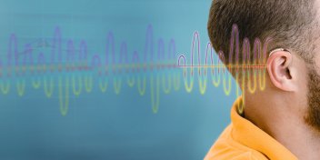 ear with a hearing aid and colorful sound waves illustrating hearing perception