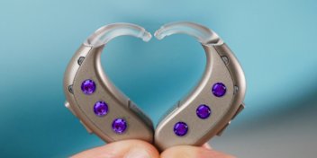 decorated hearing aids with purple gemstones forming a heart shape