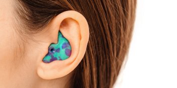 brightly colored custom ear plug fitted in an ear