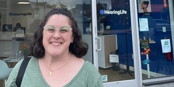 Customer standing outside a HearingLife clinic, showcasing hearing care services.