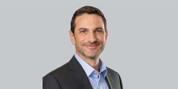 HearingLife President Dean Pappous in a gray suit and blue shirt