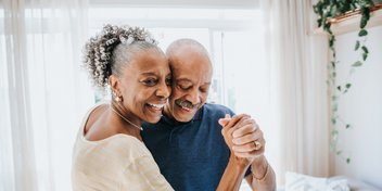 older couple joyfully dancing in a sunlit room