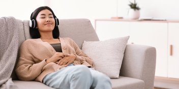 woman relaxing on a couch while using headphones for sound therapy