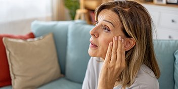 woman adjusting a hearing aid sitting on a couch