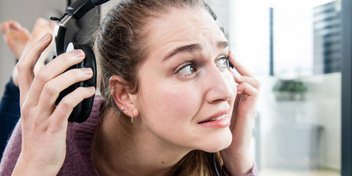 woman experiencing discomfort while wearing headphones indoors