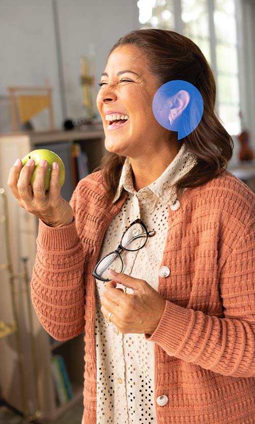 Woman smiling joyfully with a HearingLife speechbubble icon over her ear