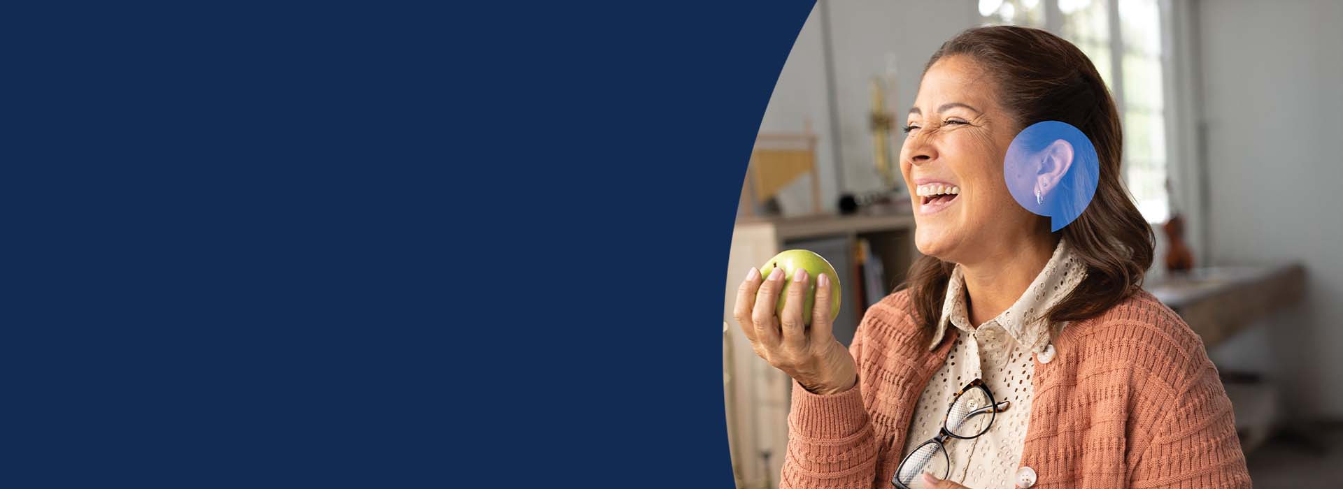 Woman smiling joyfully with a HearingLife speechbubble icon over her ear