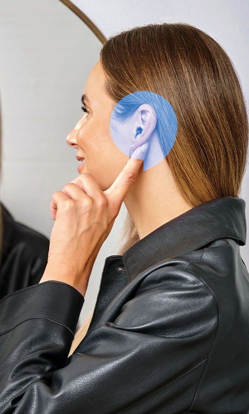 Woman wearing hearing aid and smiling into mirror