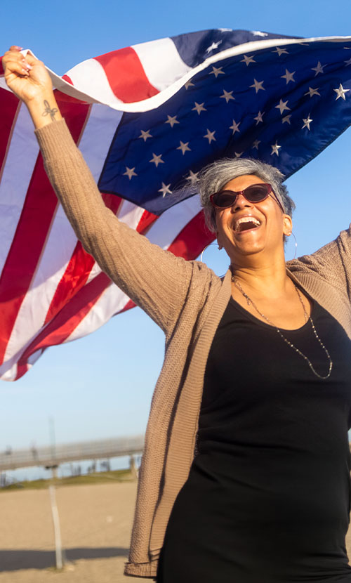 Smiling woman waving the American Flag in the wind