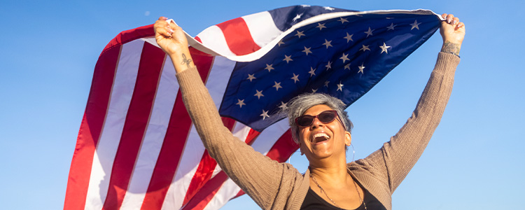 Smiling woman waving the American Flag in the wind