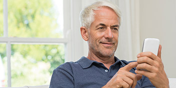 Senior man checking his smartphone in a bright indoor setting.