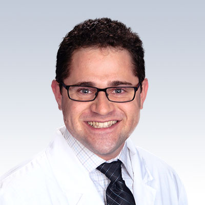 Aaron Krasnick, hearing care specialist wearing a white lab coat and tie against a gradient background
