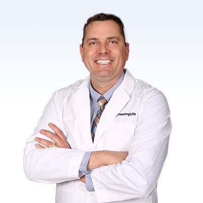 hearing care professional wearing a white coat with arms crossed, representing HearingLife