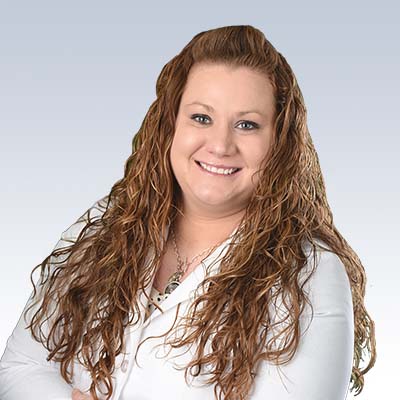 Alicia Alexander, hearing care specialist with long, curly brown hair, wearing a white blouse against a gradient background.