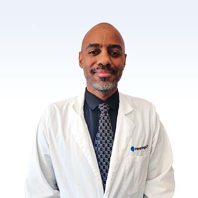 Hearing care professional wearing a white lab coat and patterned tie with a Hearing logo.