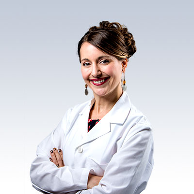 Hearing care professional wearing a white lab coat with arms crossed.