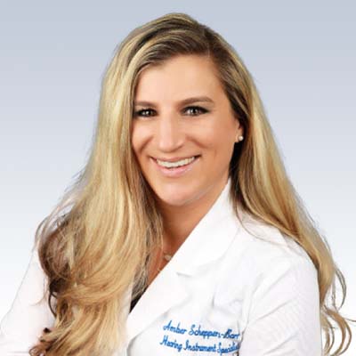 Amber Scheppers-Barr, Hearing Instrument Specialist, wearing a white coat with embroidered text.